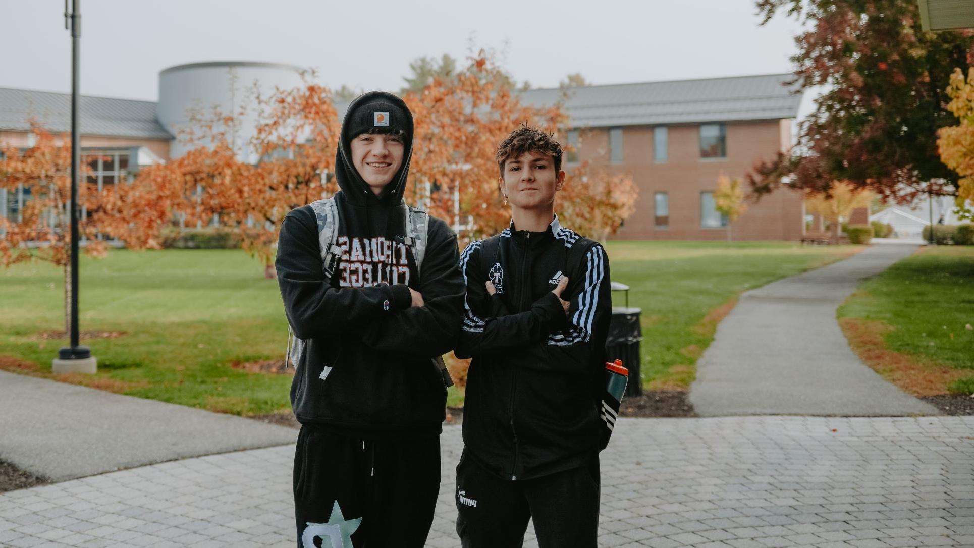 两名国际学生穿着网上网赌平台的服装，抱臂在校园里合影